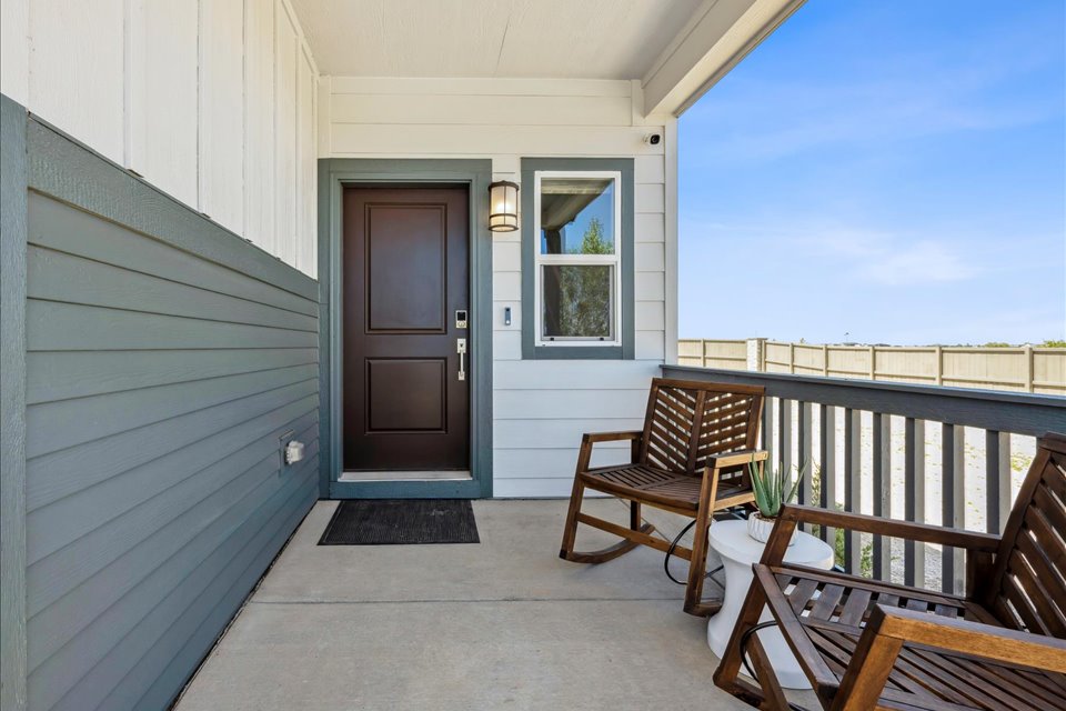 A porch with chairs and a door.