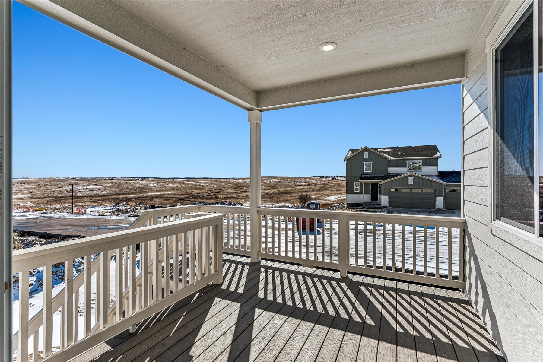 A deck with a railing and a building in the background.