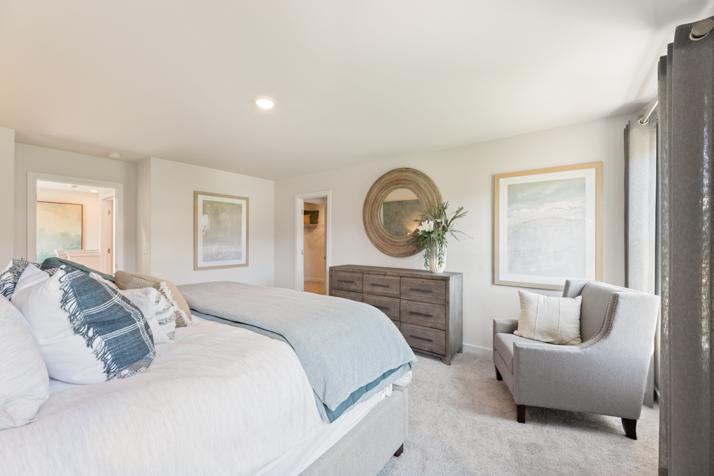 A bedroom with a bed and a chair.