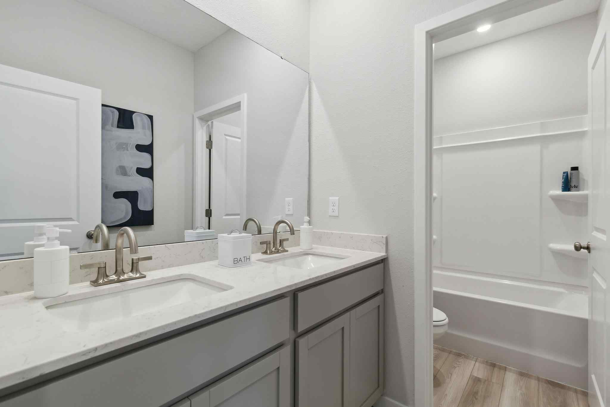 A bathroom with a tub sink and mirror.