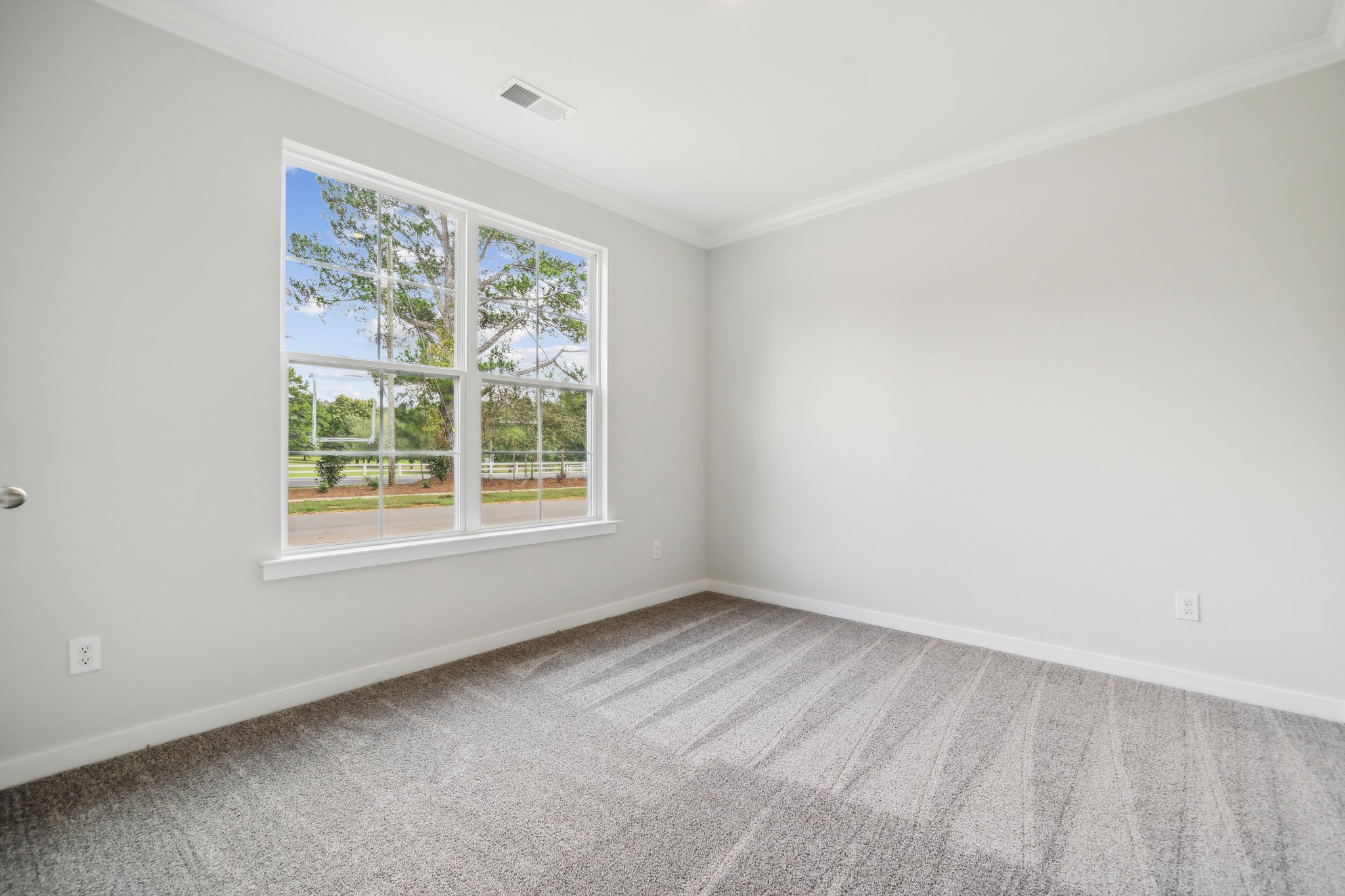 A room with a window and a white wall.