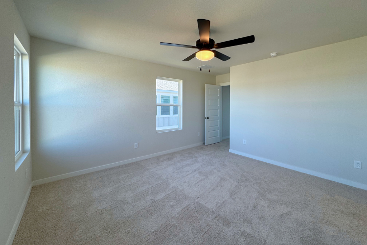 A room with a ceiling fan and a door.