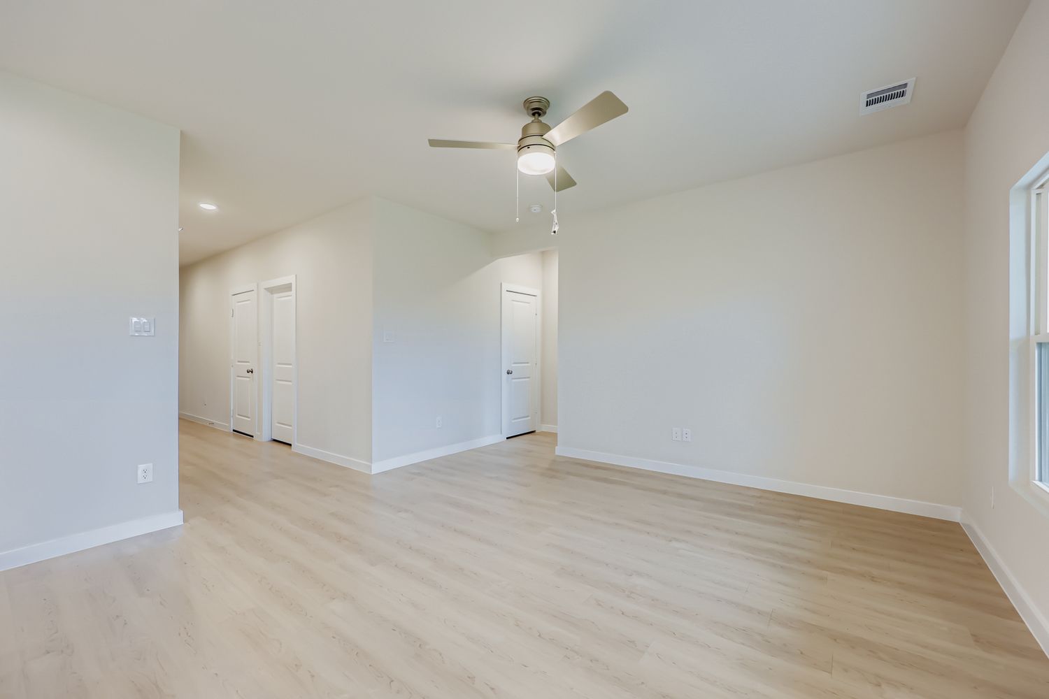A room with a wood floor and a ceiling fan.