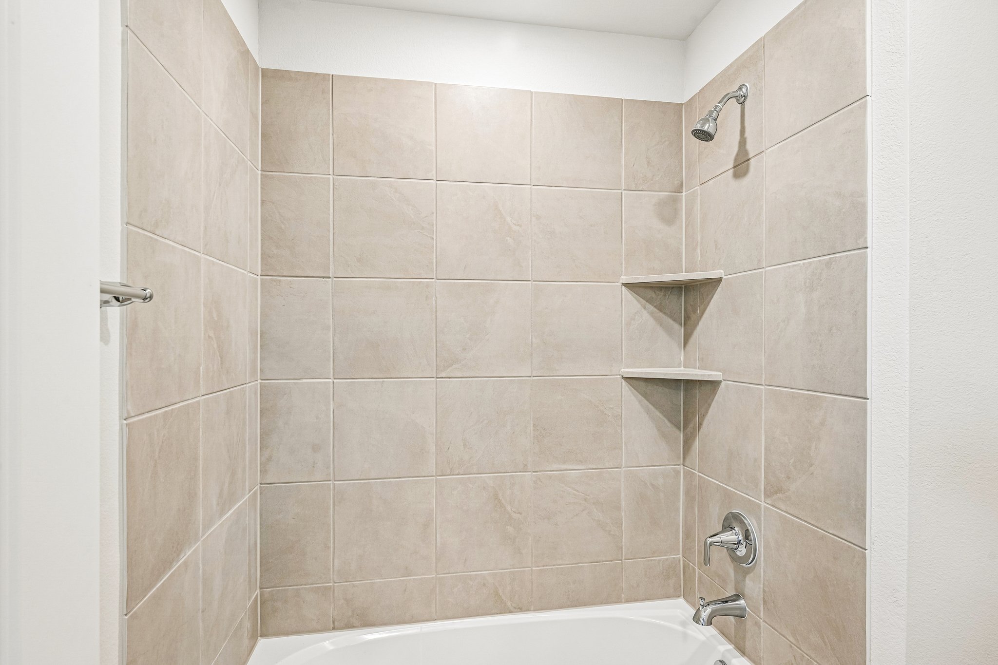 A bathroom with a bathtub and shelves.