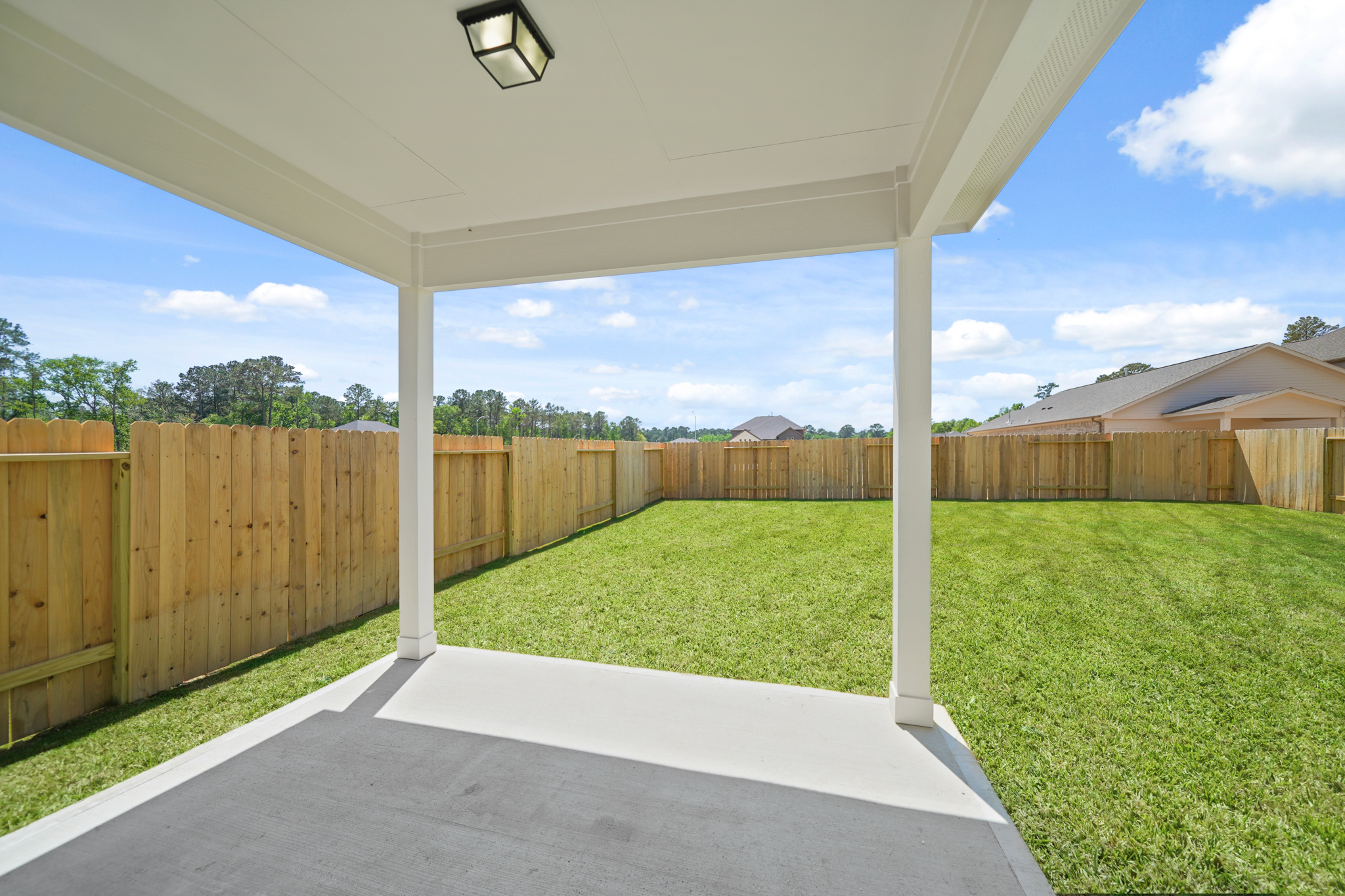 A fenced in yard with a wood gate and a light post.