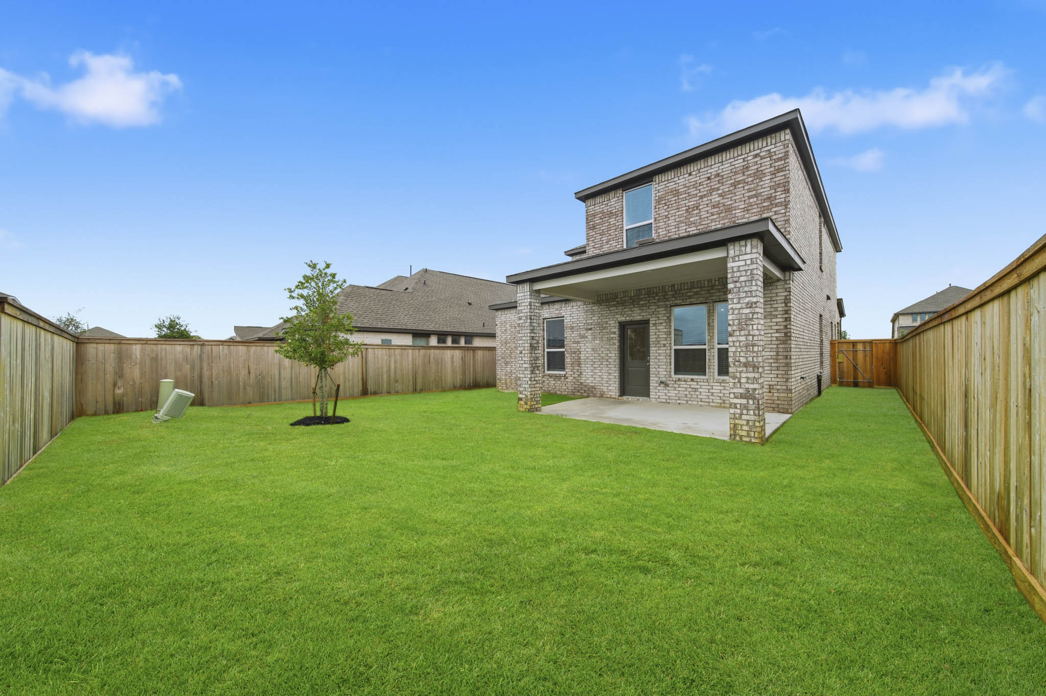 A large green yard with a fence and a tree.