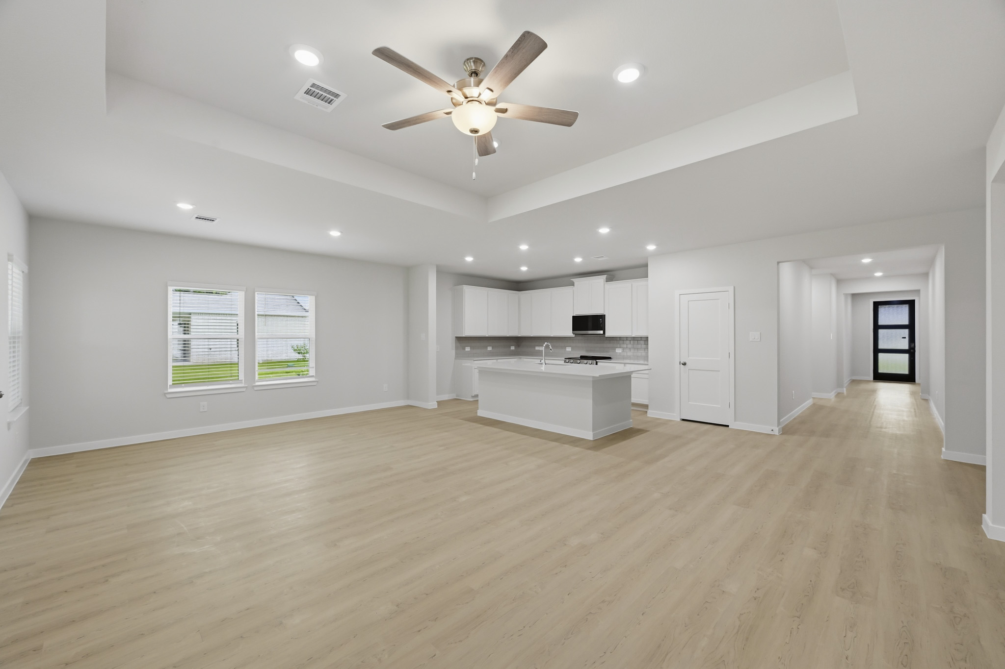 A large empty room with a wood floor and a ceiling fan.