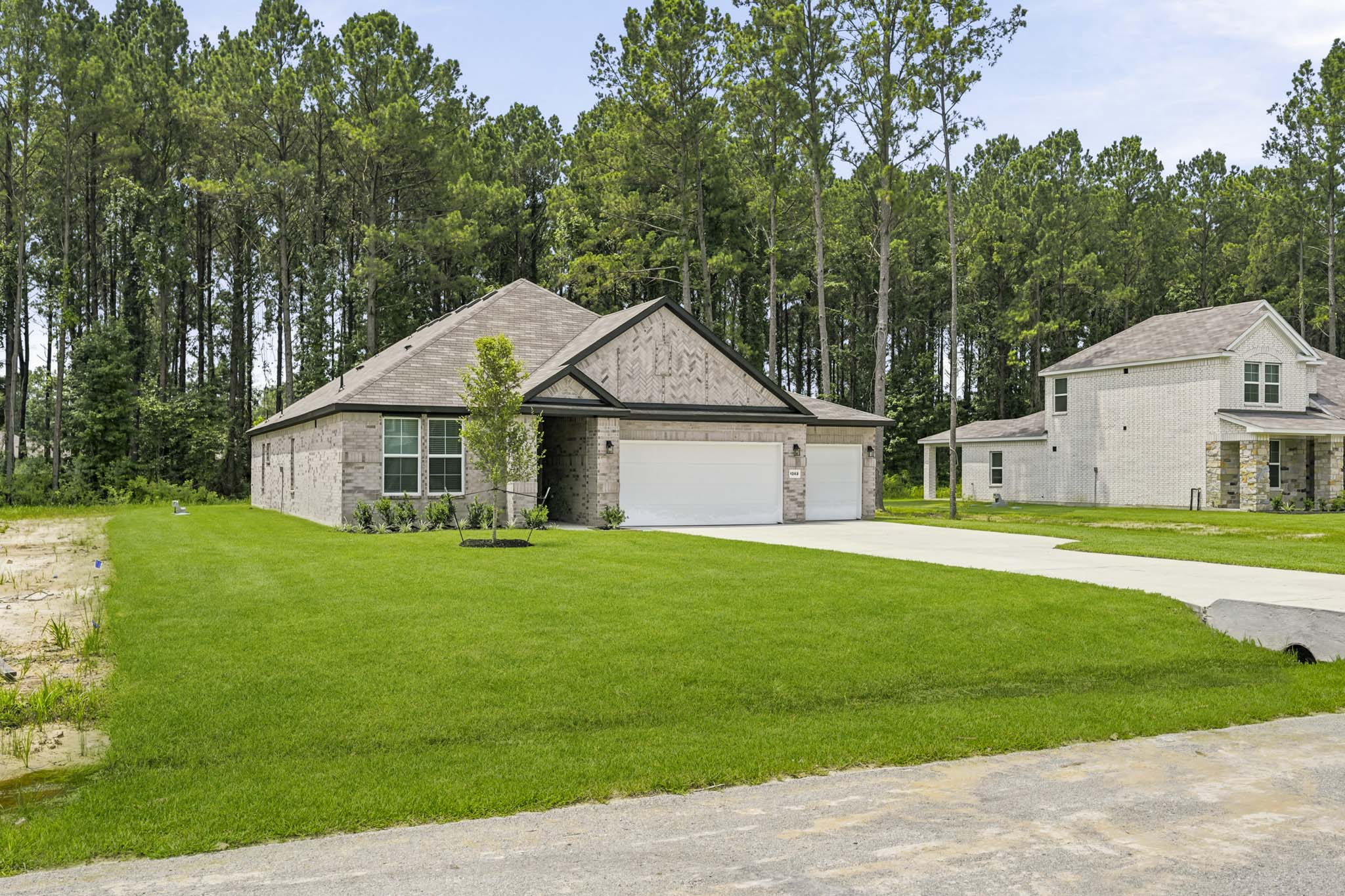 A house with a garage and trees in the back.