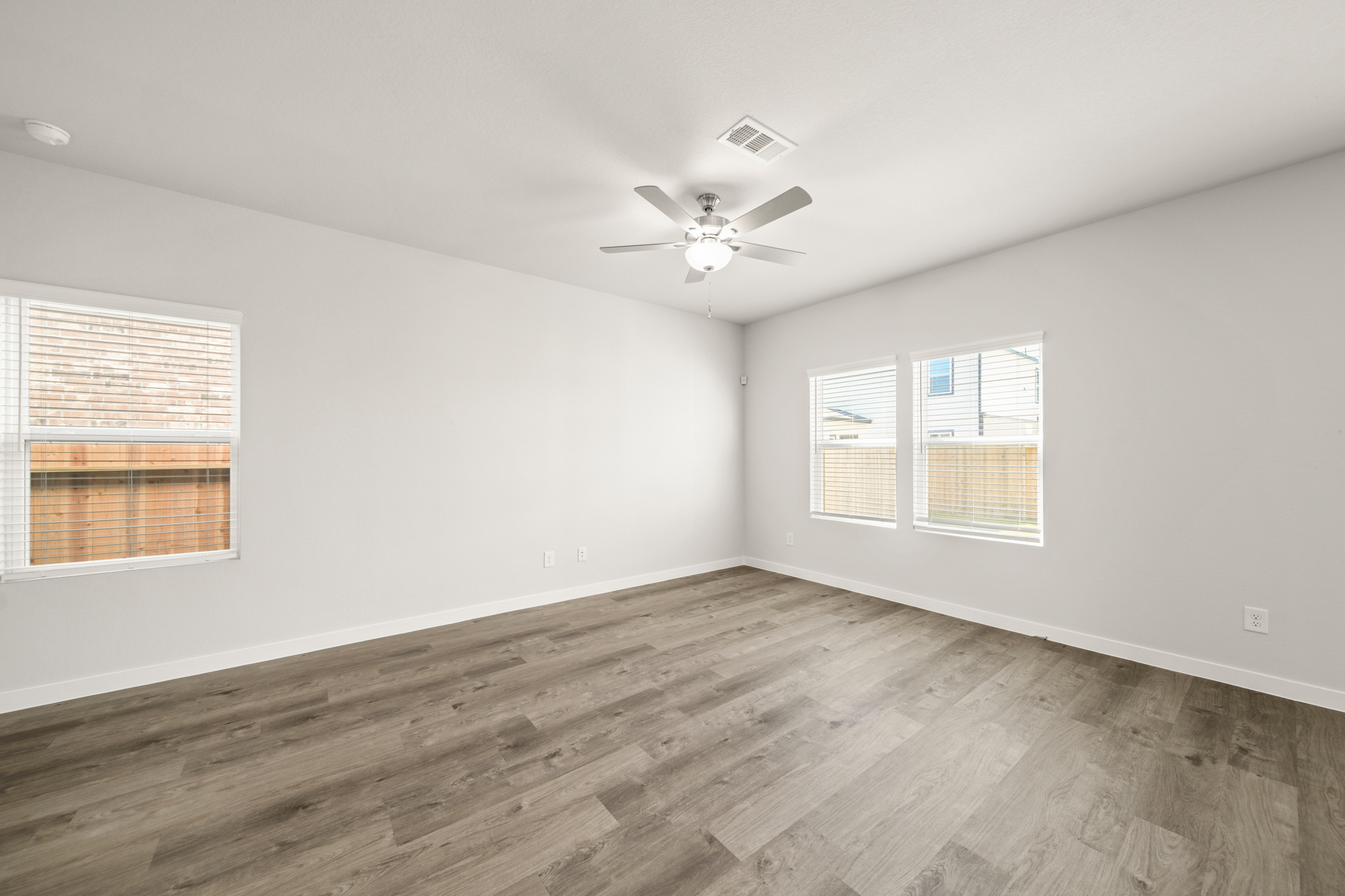 A room with a ceiling fan and a wood floor.