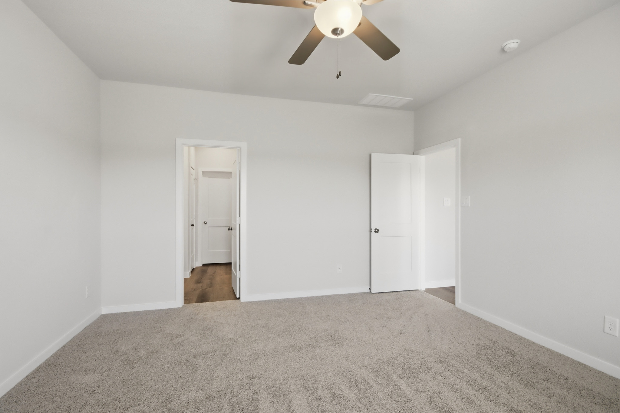 A room with a ceiling fan and white doors.