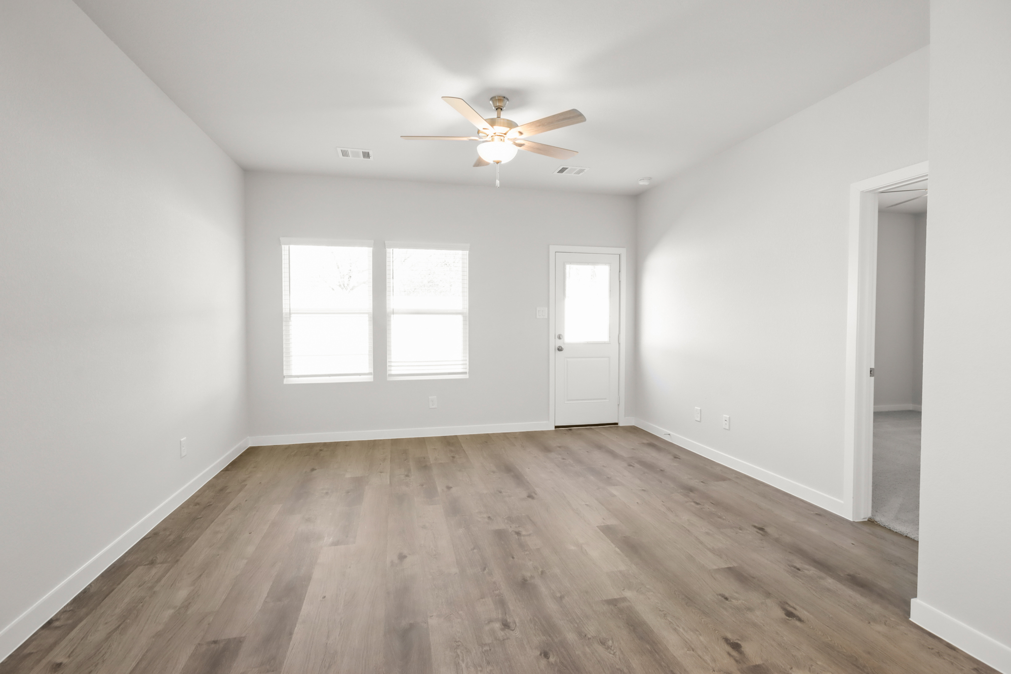 A room with a wood floor and a ceiling fan.