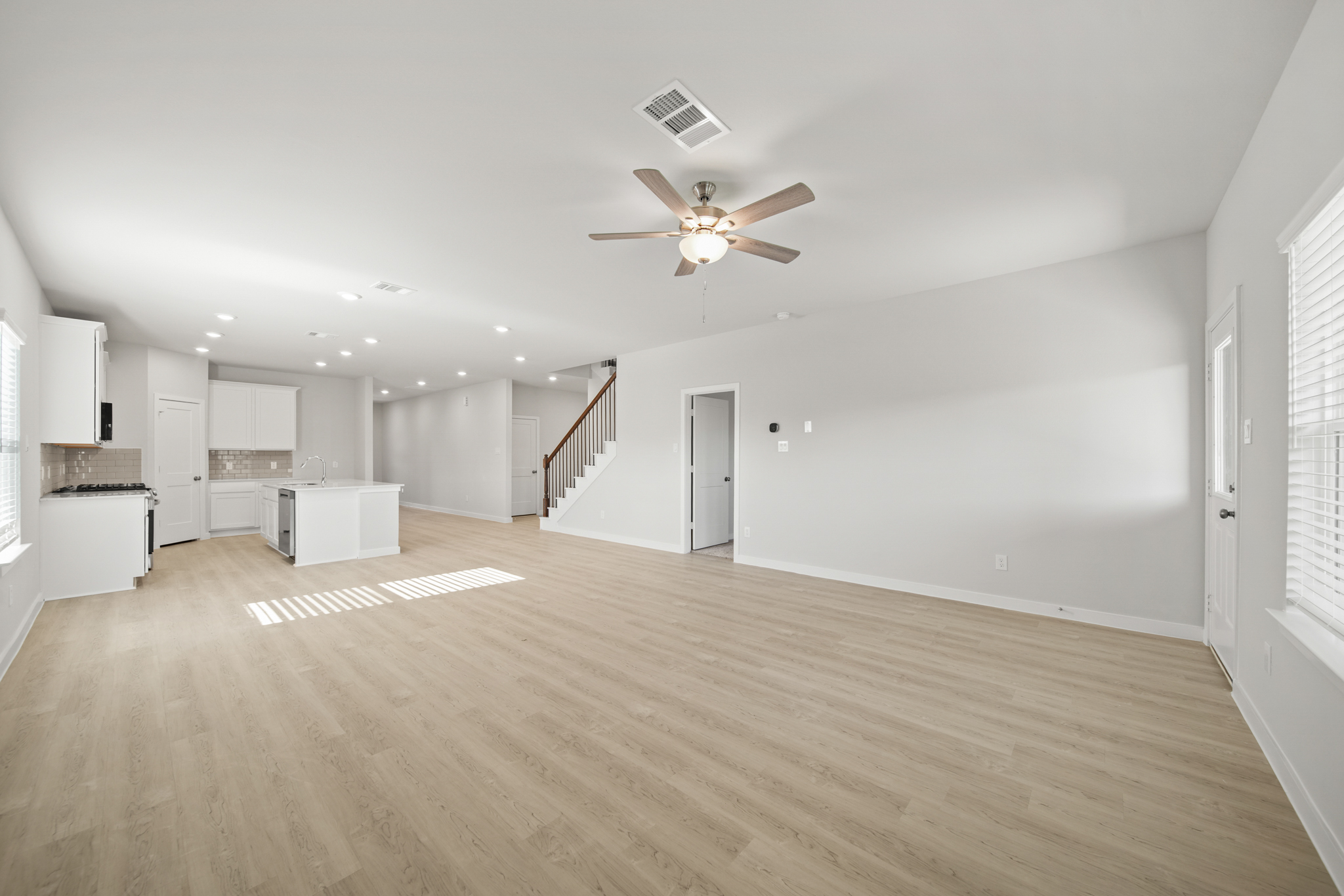 A large empty room with a wood floor and a ceiling fan.