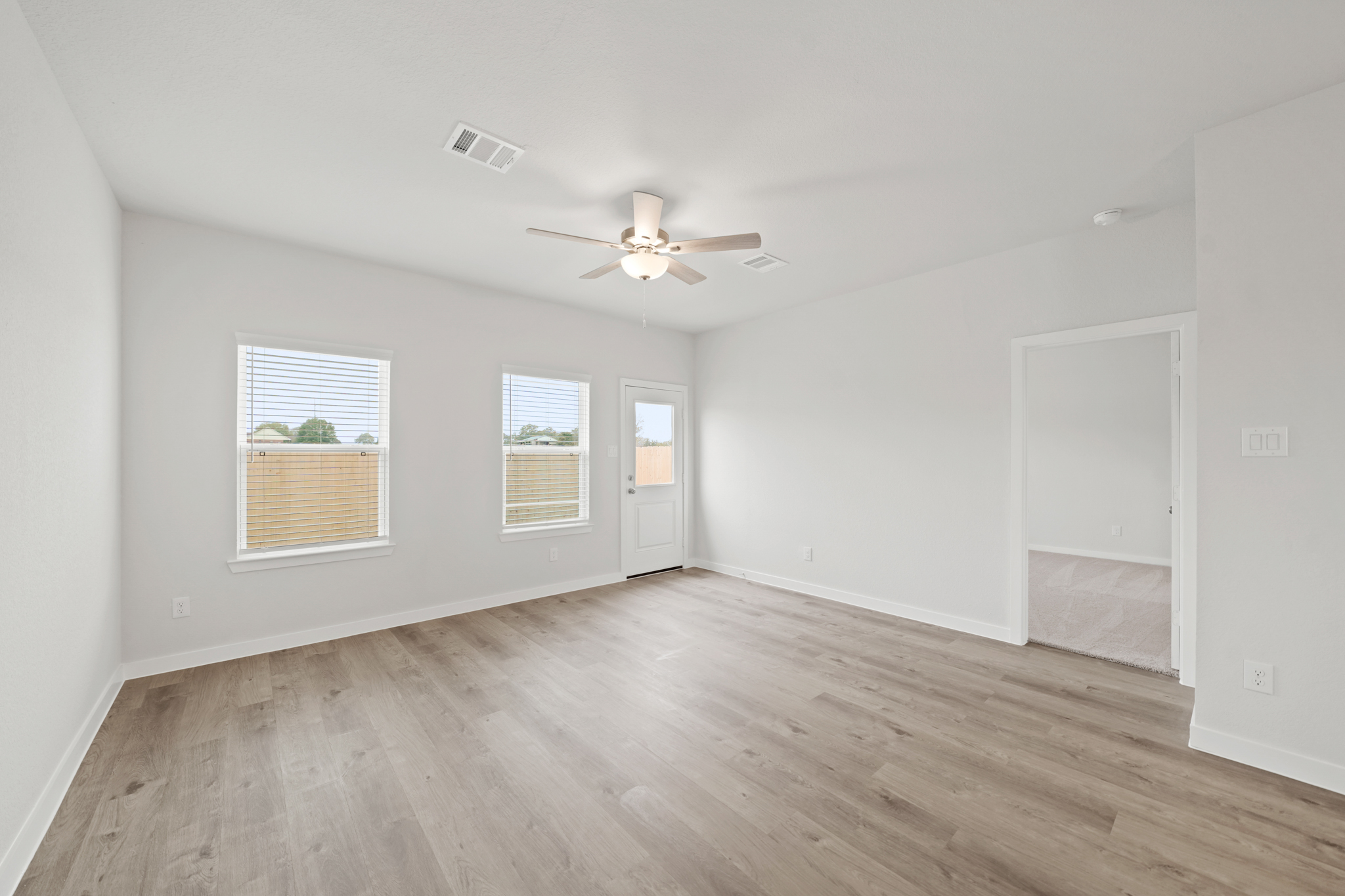 A room with a wood floor and a ceiling fan.