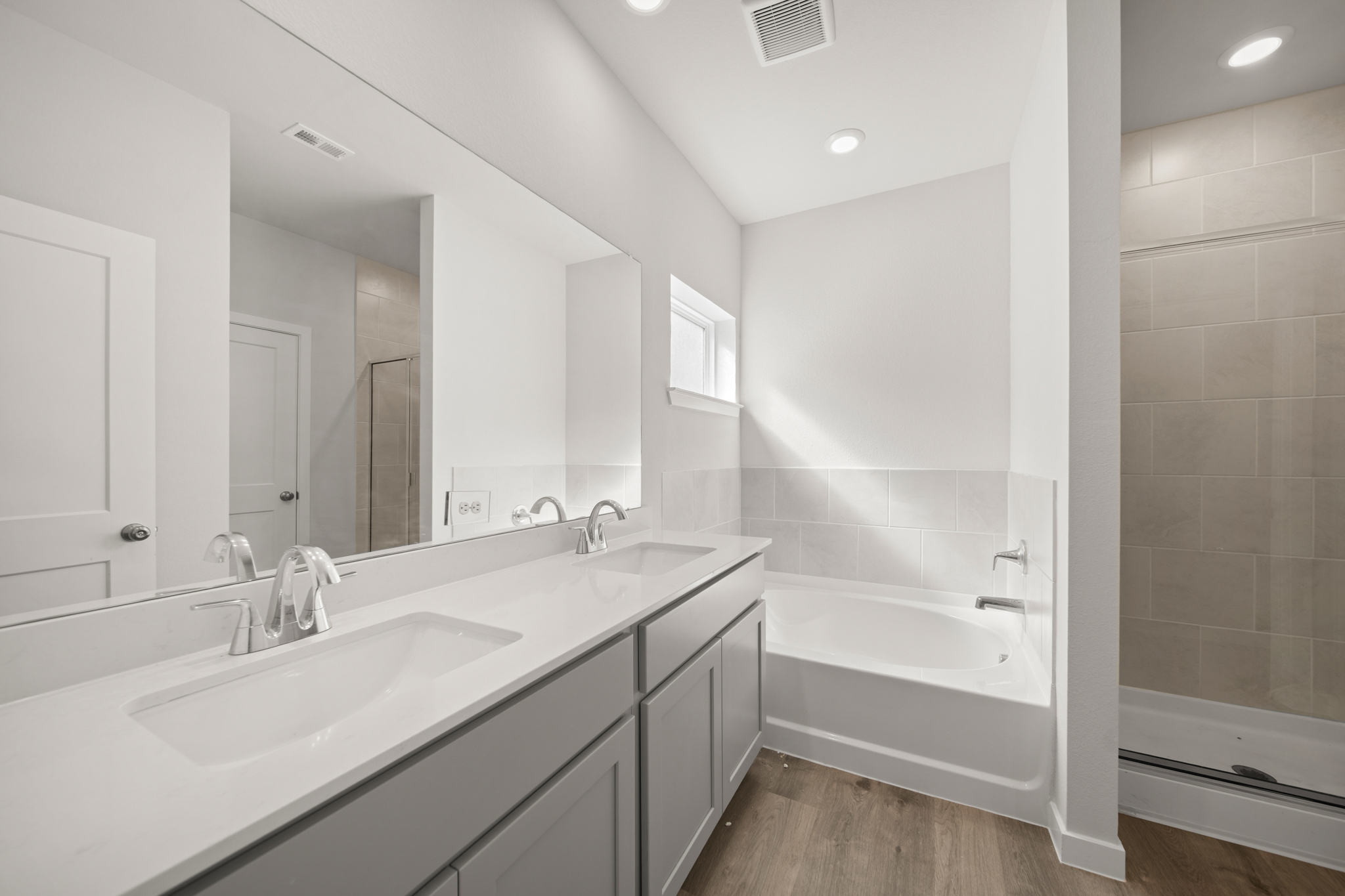 A bathroom with a tub sink and mirror.
