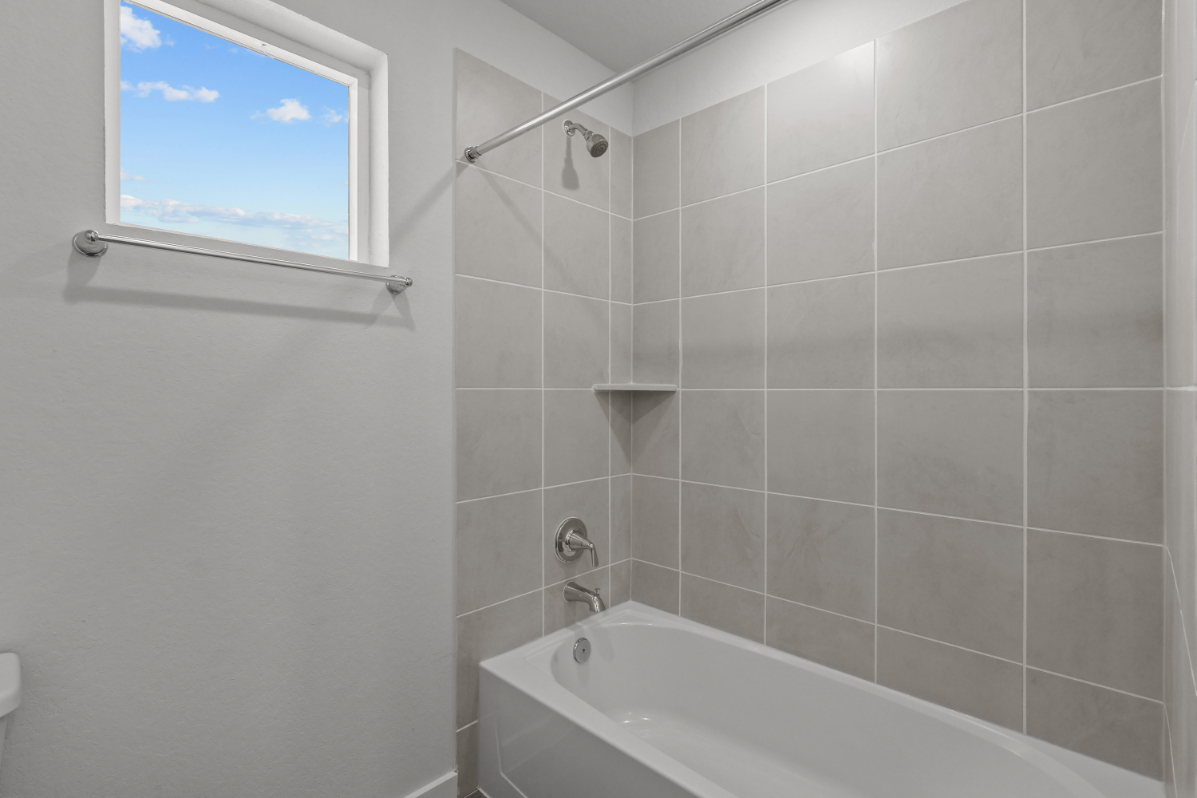 A bathroom with a bathtub and a window.