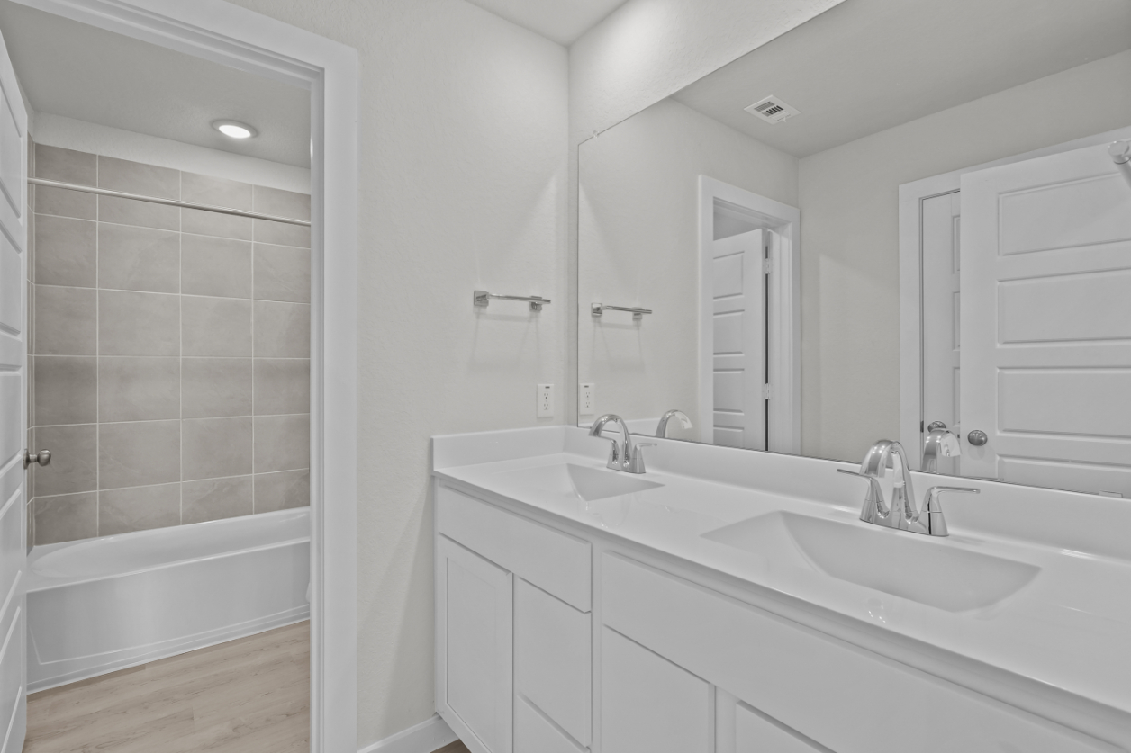 A bathroom with a tub sink and a mirror.